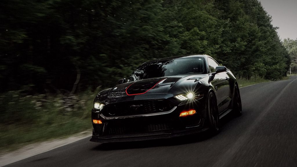 Black Ford Mustang Mach 1 rolling on a tree-lined road — ECU tuning Toronto by Wolf Performance