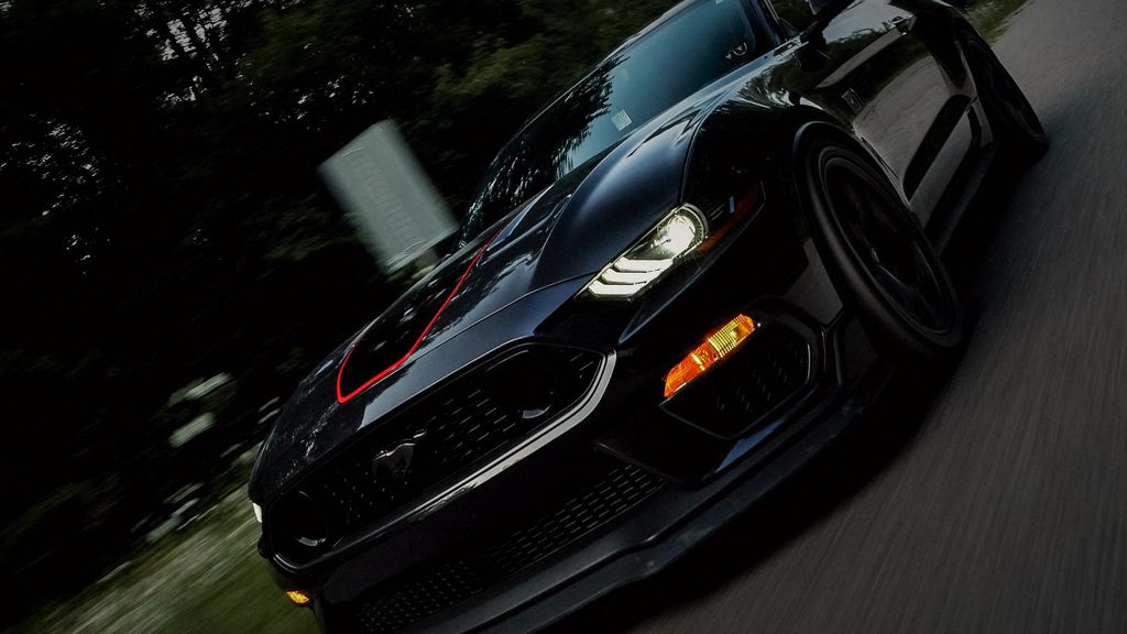 Black Ford Mustang driving on a road at night