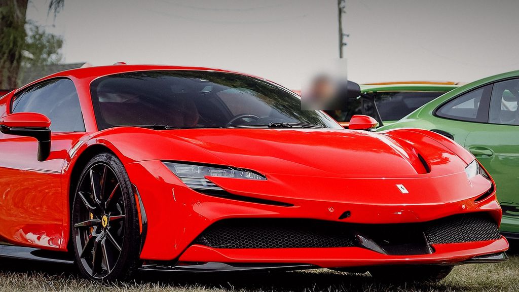 Red Ferrari SF90 parked at a car meet